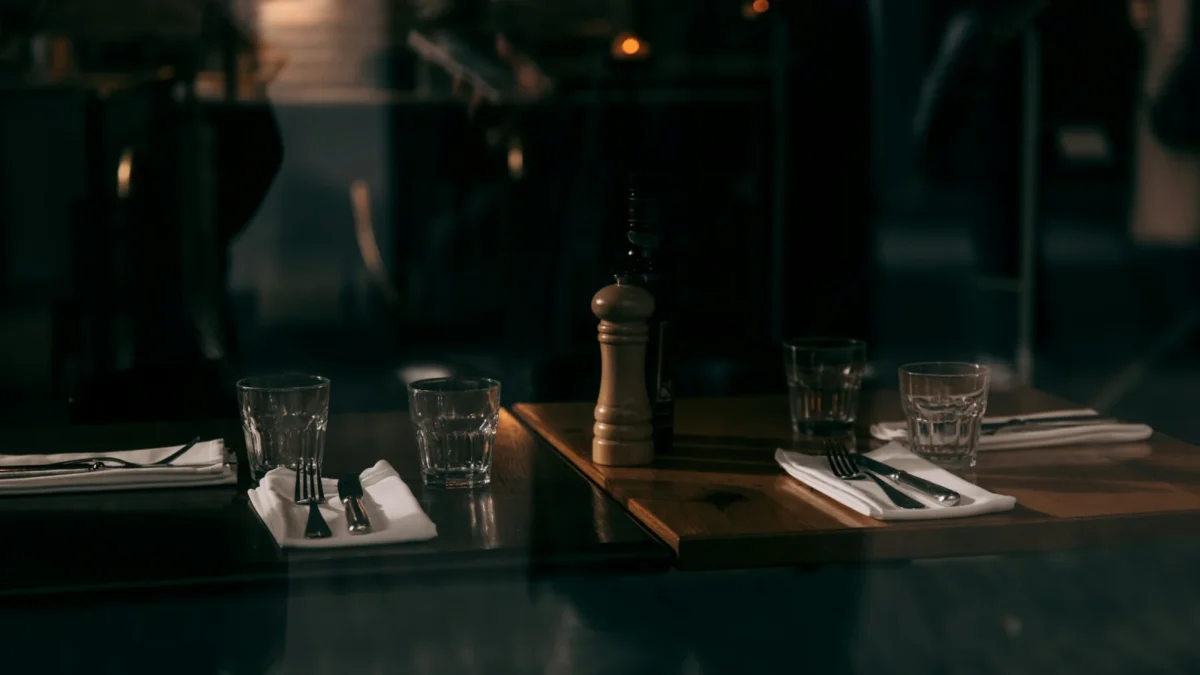 Tables set with glasses, napkins and a pepper mill in a dim dining room, a place for the best marketing tools for restaurants