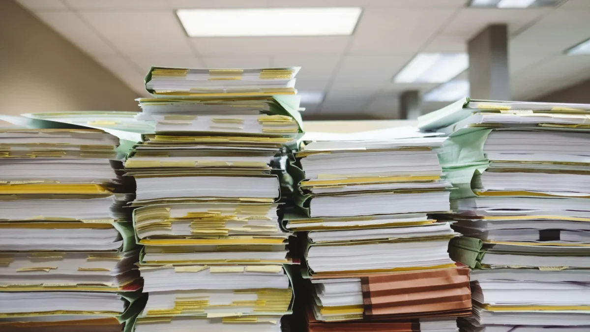 Tall stacks of paper files and folders in an office, the kind of paperwork a business loan checklist asks for
