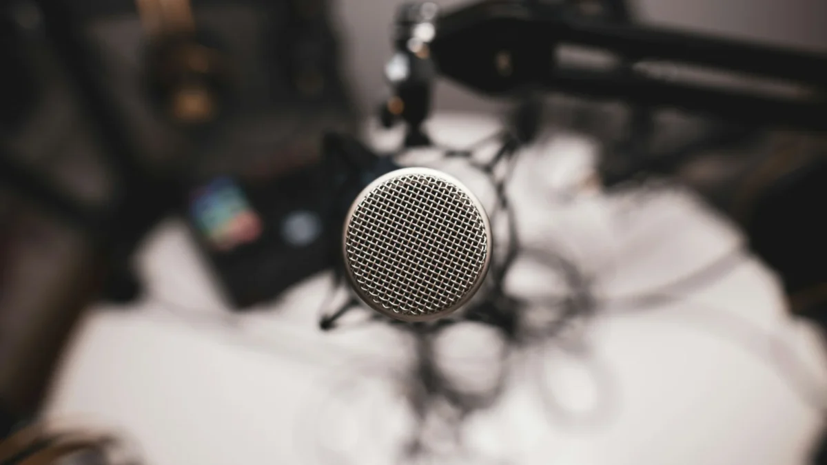 Silver condenser microphone on a stand over a cluttered desk, the kind of setup used to learn how to host a webinar