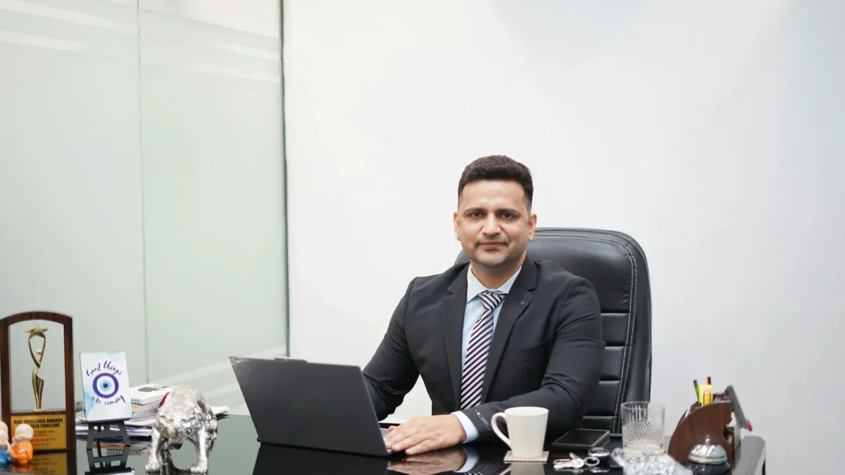 Man in suit sitting at desk with laptop and coffee