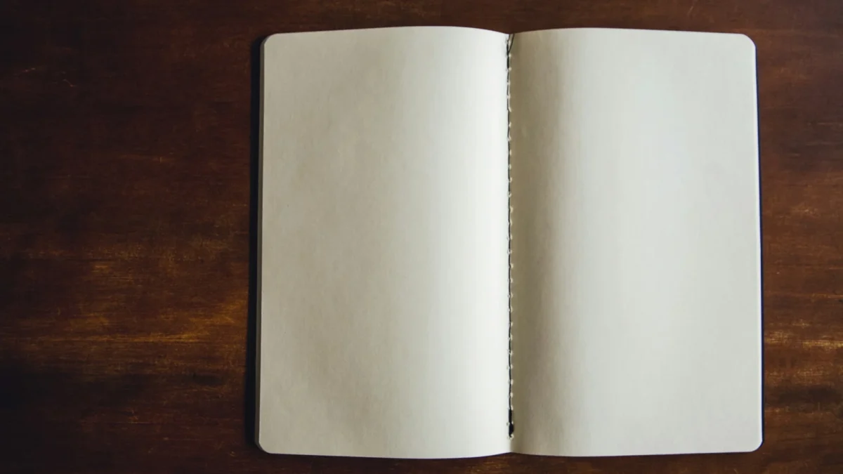 Open notebook with blank cream pages on a dark wooden table, a fresh start for workforce planning analytics